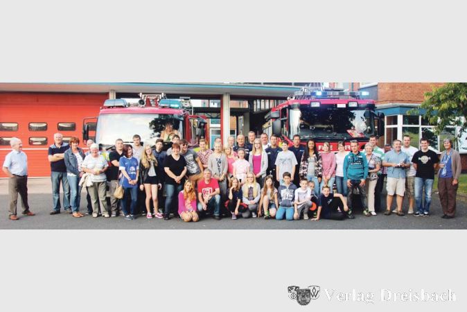 Die Bischofsheimer Nachwuchs-Brandsch&uuml;tzer, in Zivil und vermischt mit den Gastgebern auf einem Foto vereint. Im Hintergrund die Fahrzeughalle in Crewe und zwei Einsatzfahrzeuge der britischen Kollegen.

&nbsp;