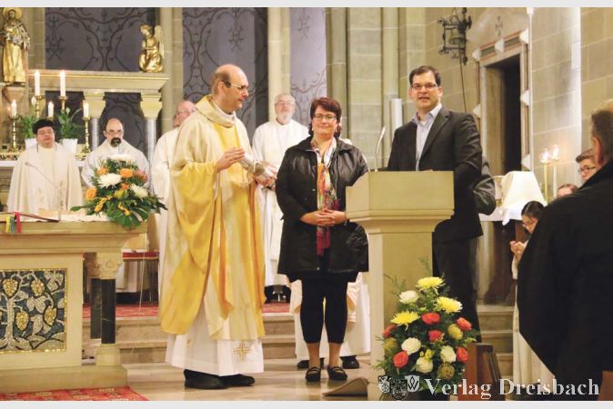 Die Vertreter der Pfarrei-Ortsaussch&uuml;sse &uuml;bergaben einen gro&szlig;en Werkzeugkasten mit &quot;Sch&auml;tzen der Gemeinde&quot;: Skizzen der drei Kirchen, die Pfarrer Klee nun betreut.