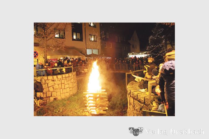 Das inmitten des Bachs entz&uuml;ndete und von der Feuerwehr bewachte gro&szlig;e Adventsfeuer l&auml;utete den Abend ein.
(Foto: A. No&eacute;)