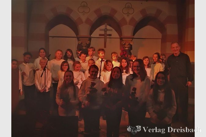 Die Kinder der Riedschule beim diesjährigen Adventskonzert, rechts Musiklehrer Henning Schütz.
