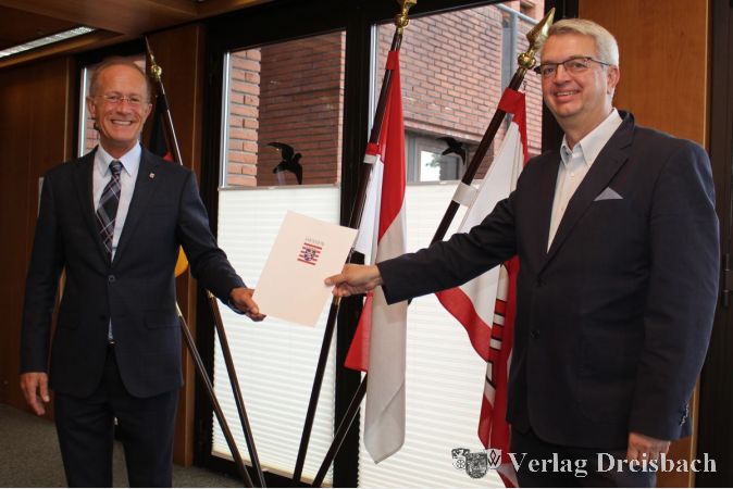 Staatsminister Axel Wintermeyer (links) überreicht den Bescheid an Bürgermeister Dirk Westedt (rechts).
