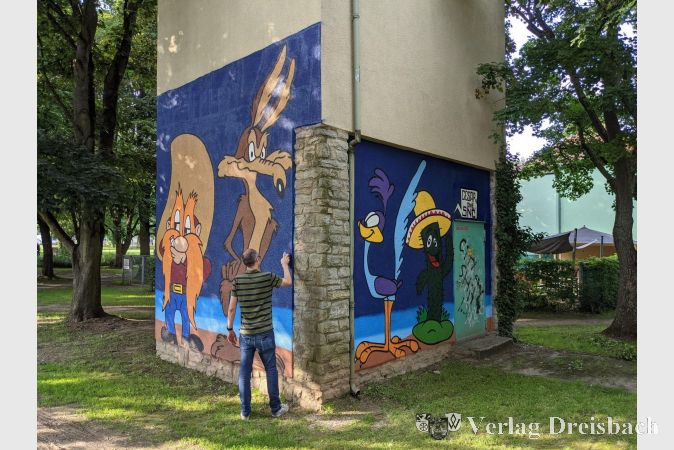 Der Graffiti-Künstler Cesar One vor den beiden in diesem Monat neu gestalteten Seiten des Stromverteilerhäuschens in der Grünanlage Am Weiher.
