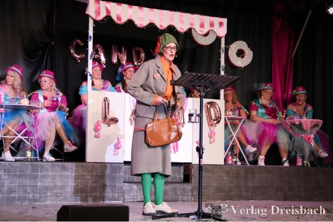 Appolonia berichtet über die Schwierigkeiten beim Gendern. Im Hintergrund auf der Bühne die Wilden Weiber Okriftel im Candy-Land.