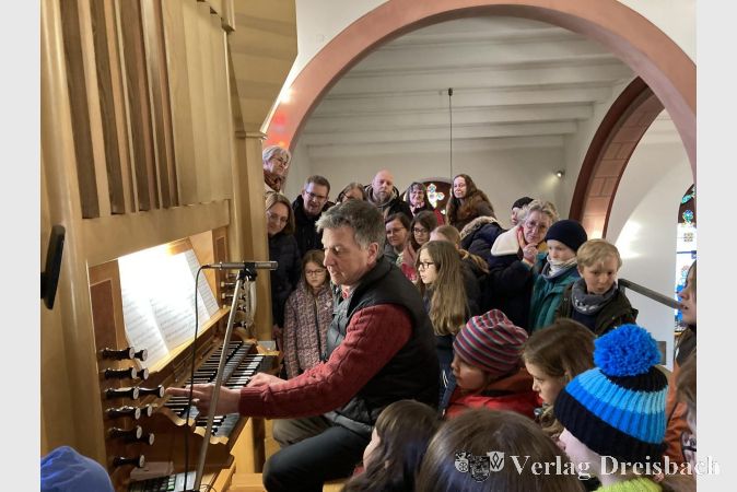 Andreas Winckler an der Orgel umringt von wissbegierigen Kindern.