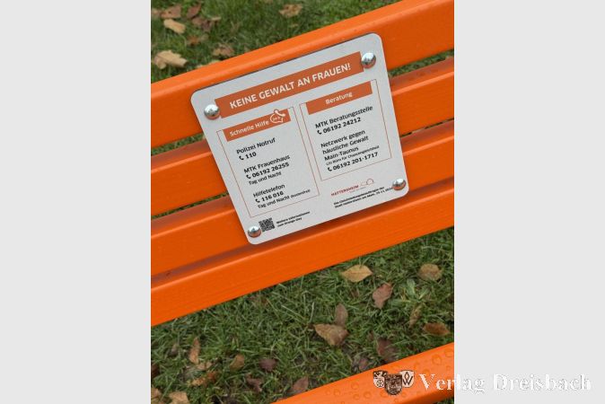 Die Bank verfügt über ein Schild, das über wichtige Telefonnummern für Frauen in Not informiert.