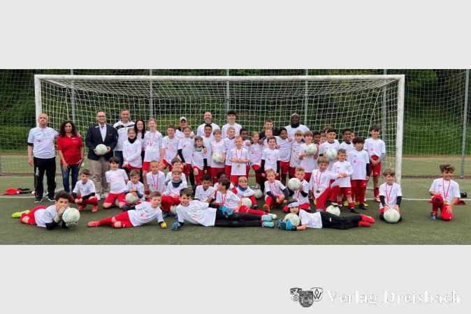Christoph Barthenheier, Karima Khabbach, Stephan A. Kietzmann und Alexander Schur (hintere Reihe v.l.) nach dem Abschlussturnier inmitten der Teilnehmenden des diesjährigen Naspa-Fußballcamps in Flörsheim.