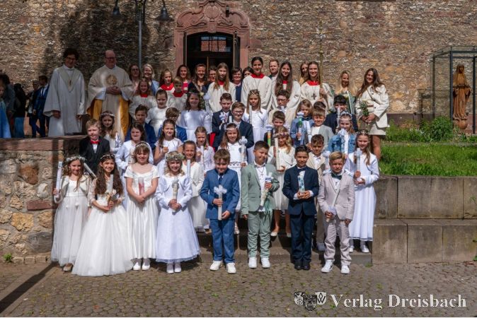 Die 32 Kommunionkinder aus St. Gallus und St. Josef strahlen an ihrem großen Tag – begleitet von ihren Katechet:innen und Pastoralreferentin Caroline Schneider und Pfarrer Friedhelm Meudt.
