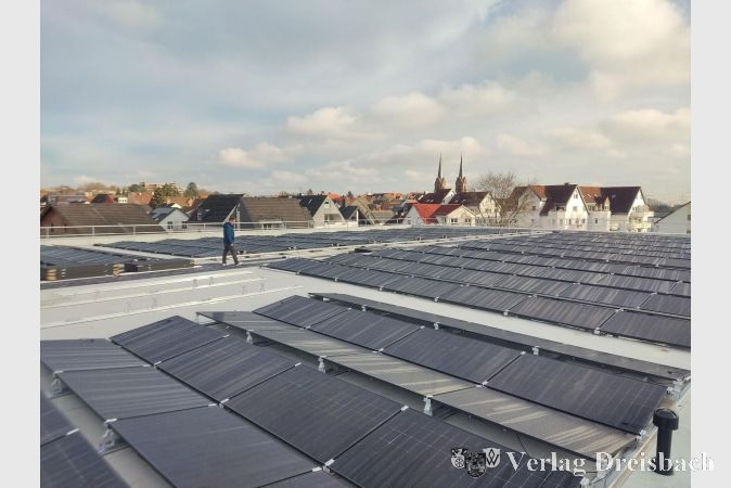 Der Erste Beigeordnete Martin Mohr schaut sich die beeindruckende Photovoltaik-Anlage auf dem Dach der großen Halle an.