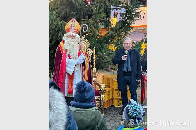 Nikolausbesuch: Pfarrer Friedhelm Meudt in der Rolle des Nikolaus verteilt gemeinsam mit Bürgermeister Bernd Blisch Weckmänner an die Kinder.