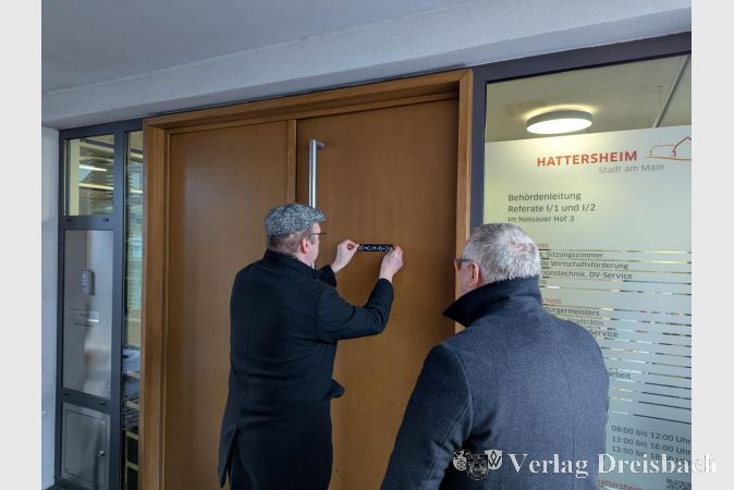 Pfarrer Andreas Klee beim Anbringen des Segensaufklebers an der Rathaustür.