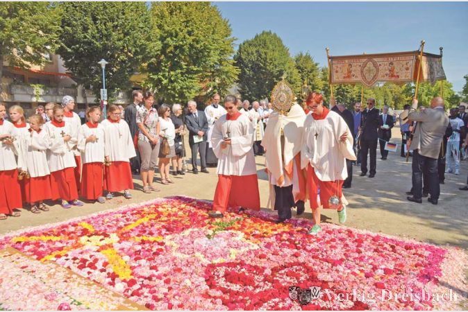 Fotos: R. Dörhöfer
"Der Zukunft ein Gesicht geben" – so hatten die Messdiener den Jugendaltar am Mainufer überschrieben. Der von ihnen gelegte prächtige Blumenteppich zeigte Symbole der Kraft, die sich zu einem harmonischen Ganzen fügten. Die unter der heißen Sommersonne besonders intensiv duftenden Rosenblätter verstärkten die Wirkung des gewählten Bildes.